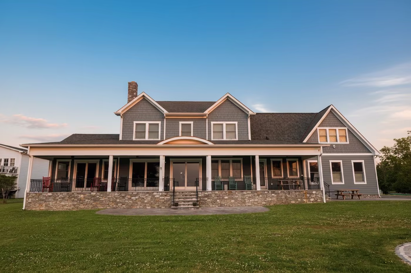 Tudor-style brick and stucco ranch home illuminated at dusk with manicured landscaping and a curved driveway