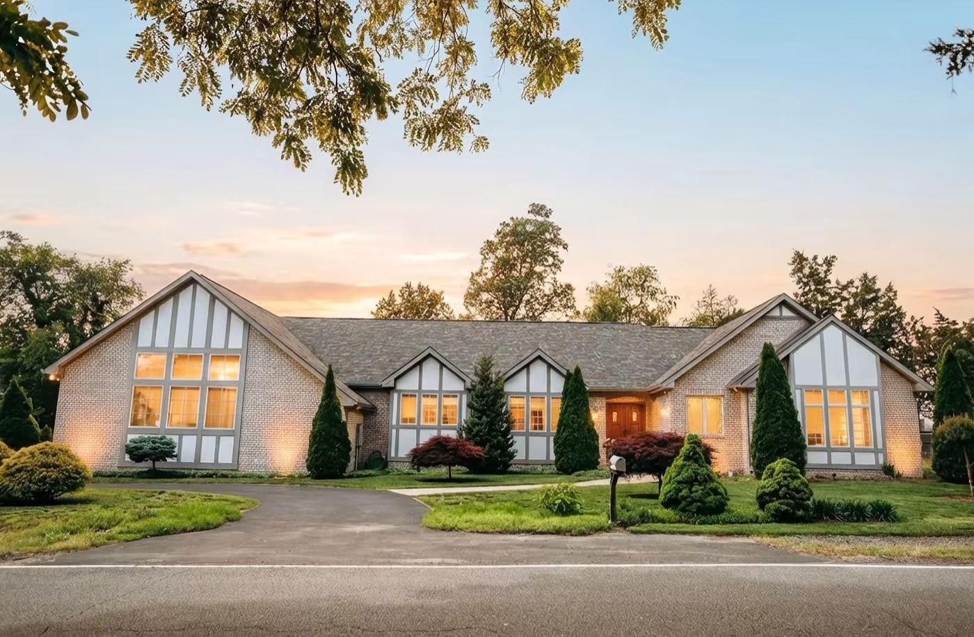 Navy blue craftsman ranch home with stone accents, an arched wood front door, and a two-car garage