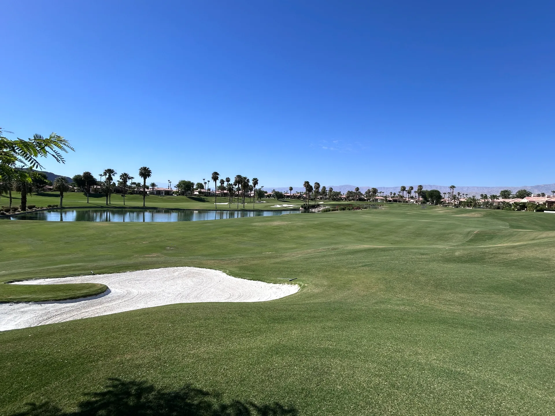 A scenic view of a luxury golf course community lake and fairway in La Quinta, California, where we provide 24/7 emergency water heater services.