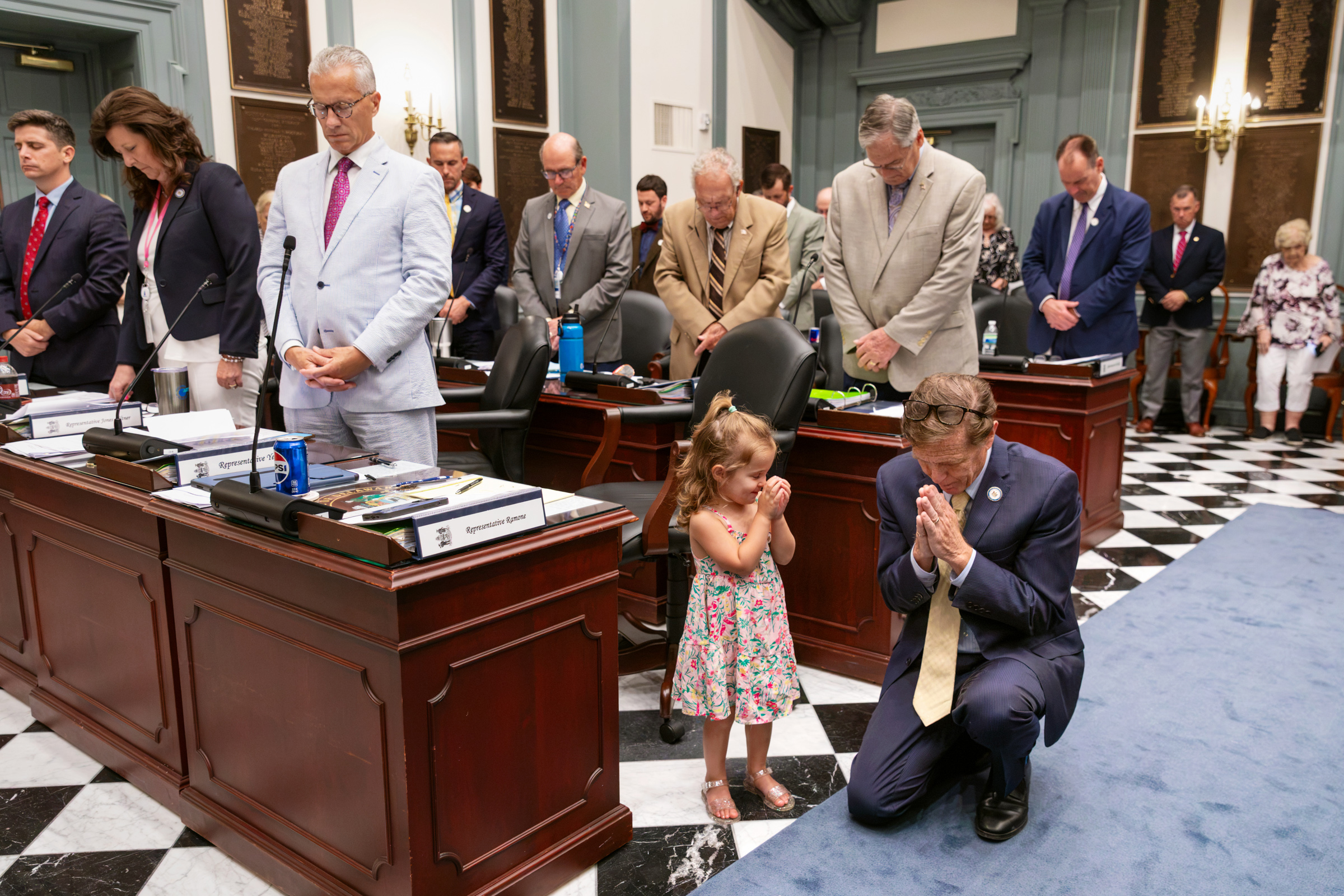 Young girl joins her grandfather in prayer on the Delaware House floor before the legislative session begins.