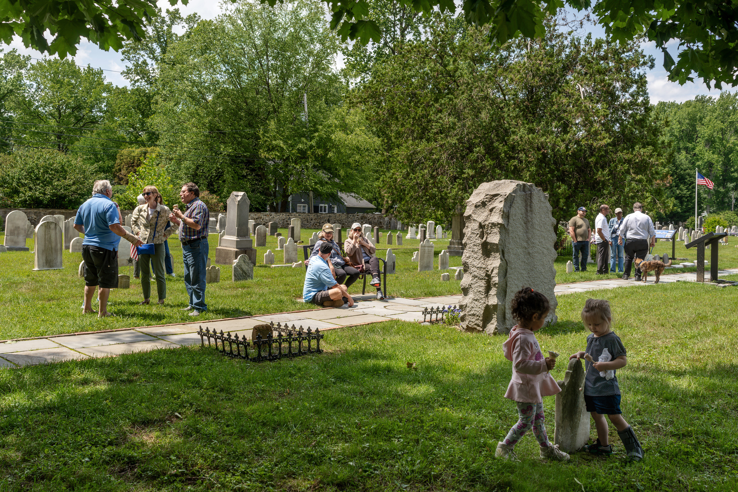 People gather, talk, and enjoy ice cream during a community event in a historic cemetery.