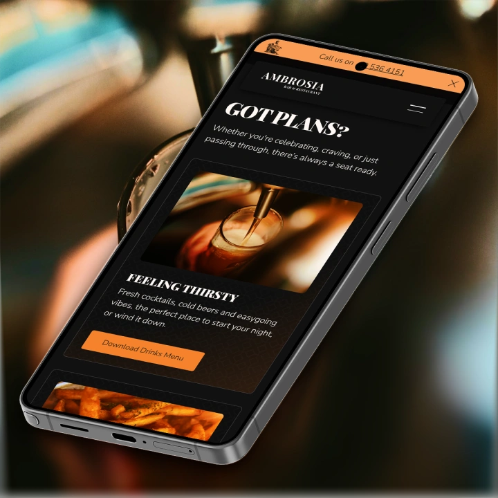 Smartphone screen shows Ambrosia Bar Restaurant website promoting drinks menu with a beer being poured image.