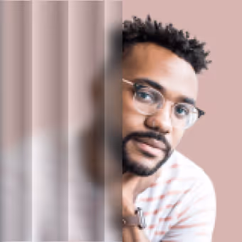 Man with glasses and a beard, partially obscured by vertical frosted glass panels.