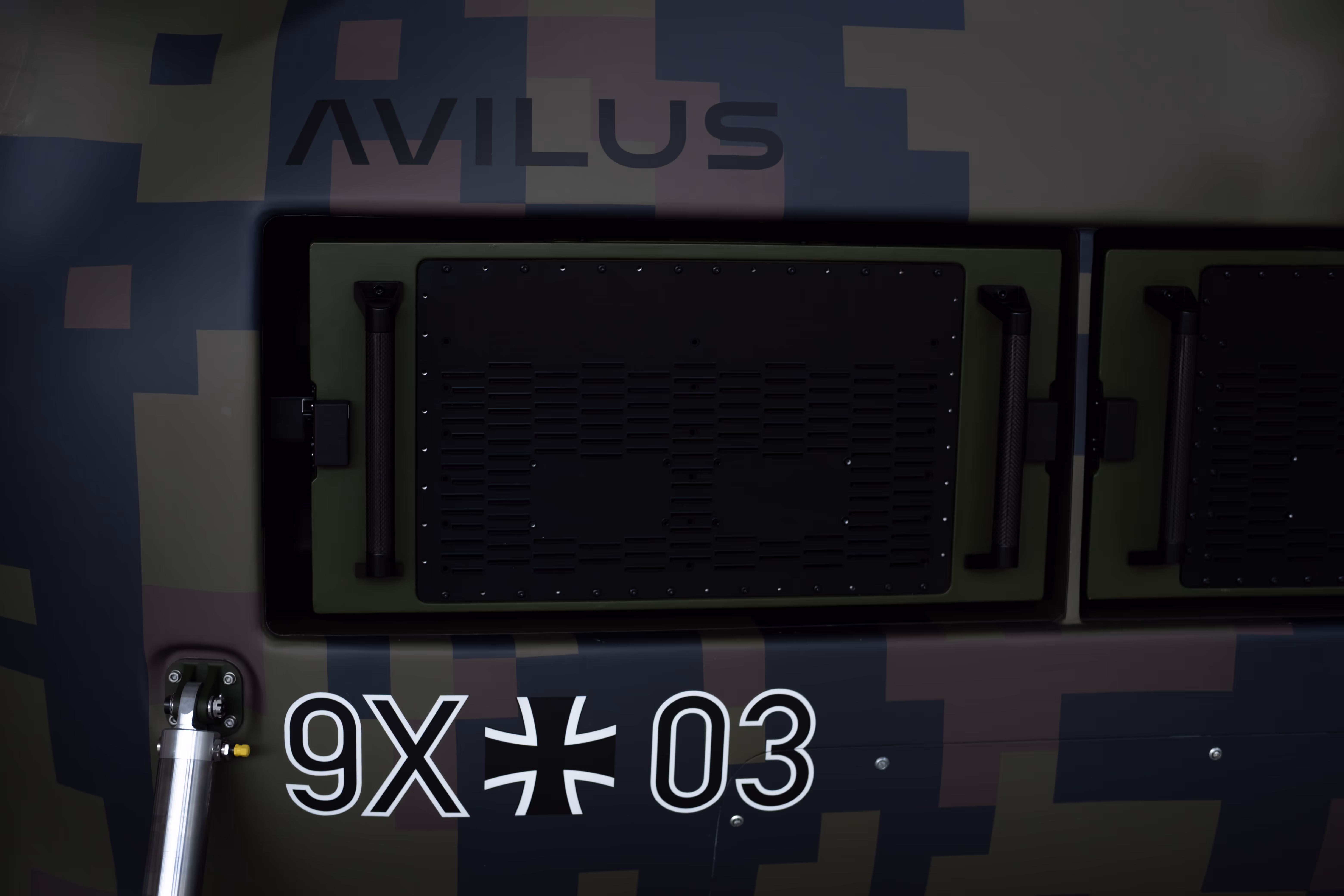 Avilus lettering and 9X-03 designation on the Grille drone's camouflaged fuselage panels.
