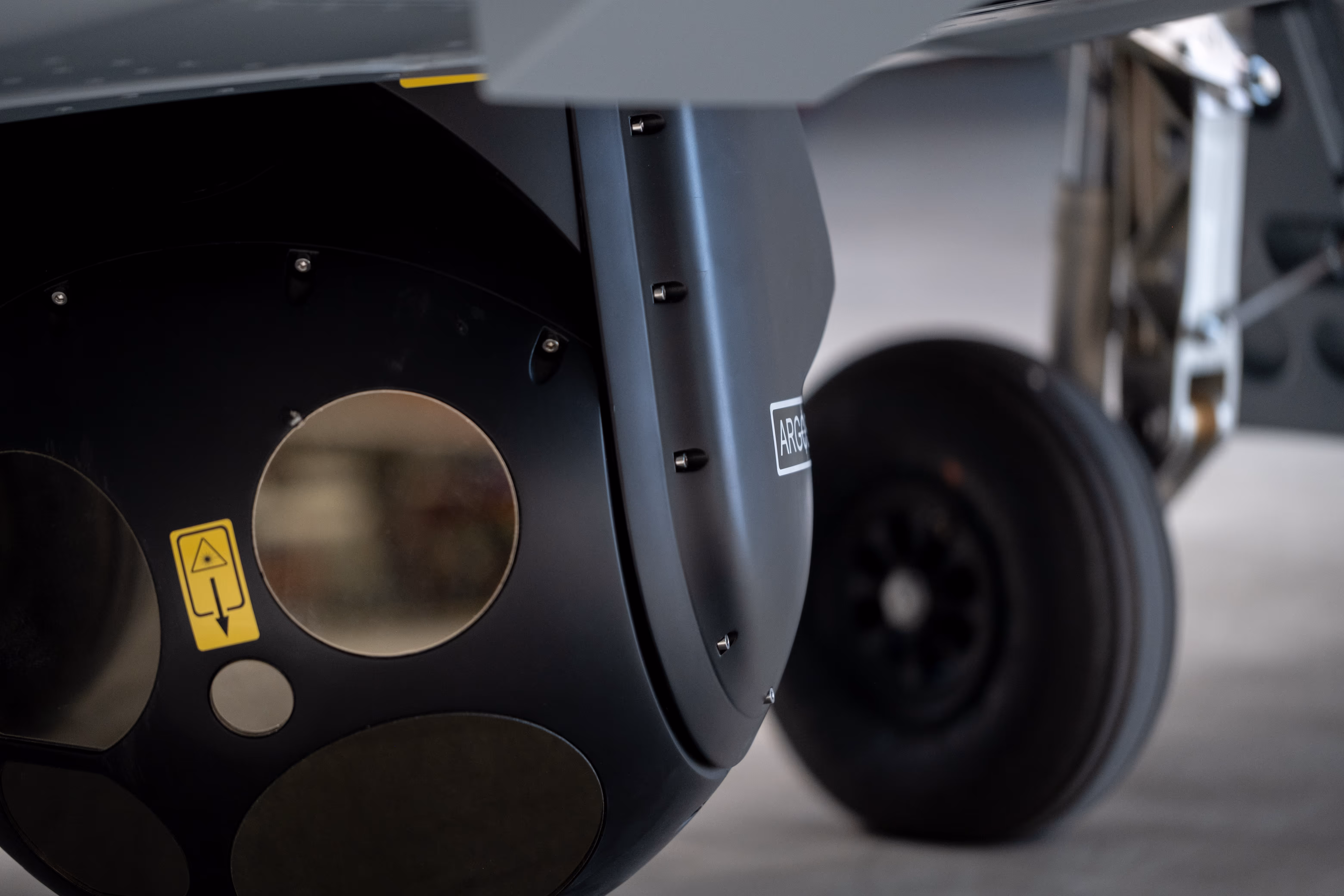 Sensor gimbal turret and landing gear wheel beneath the Bussard drone.
