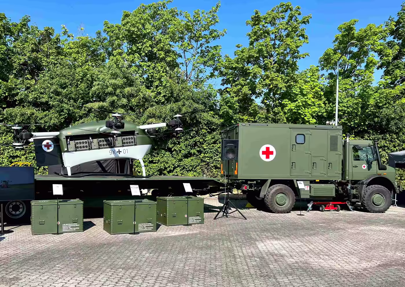 Grille drone and military ambulance beside stacked transport boxes