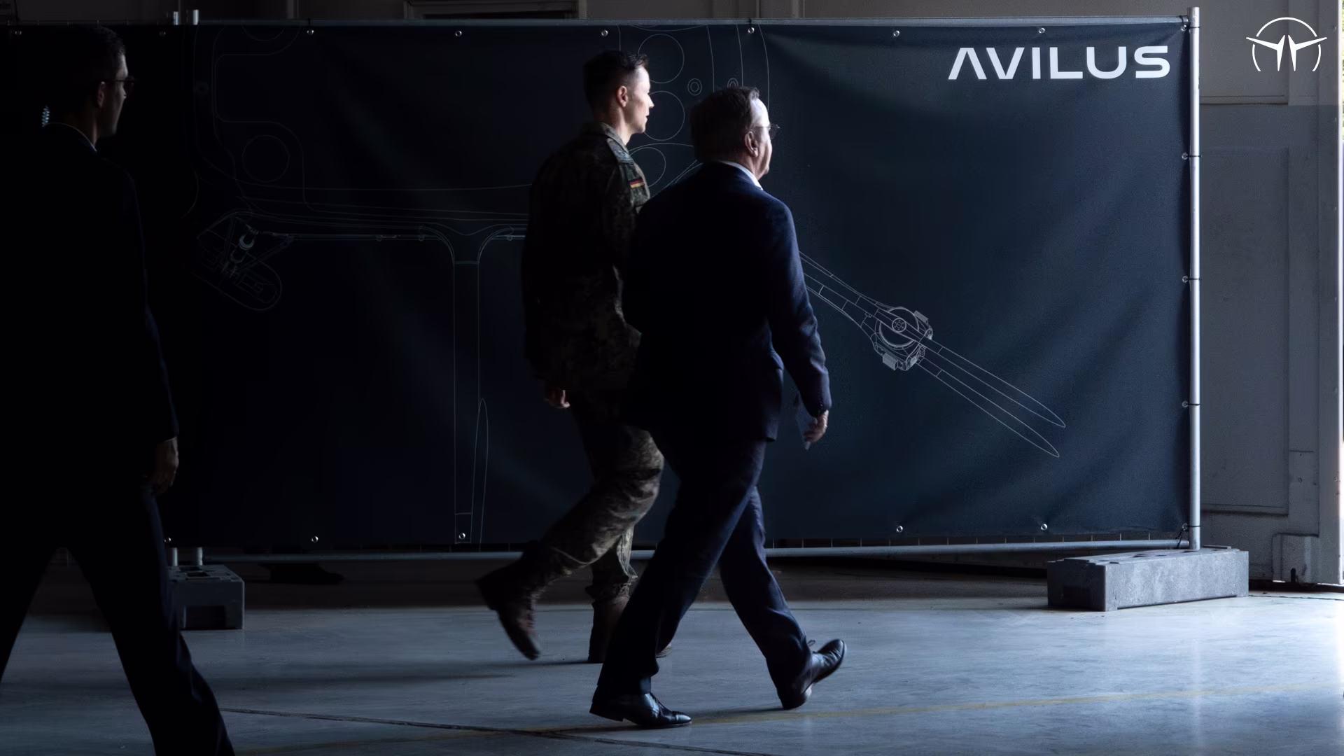 Two men walking past an Avilus display panel
