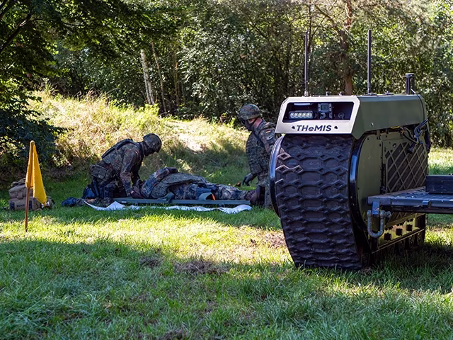 Soldiers treating a casualty next to a THeMIS ground robot
