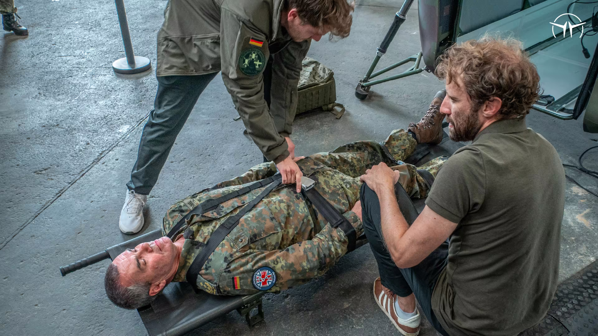 Instructors practising casualty handling on a stretcher in a hangar