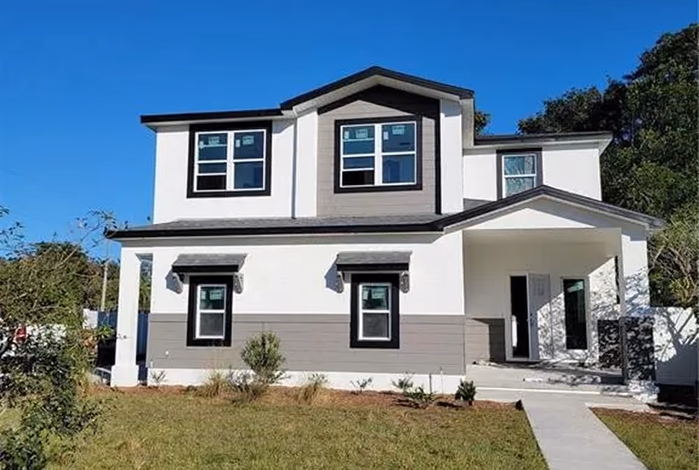 Two-story modern house with white and gray siding, multiple windows, front porch, and a concrete walkway.