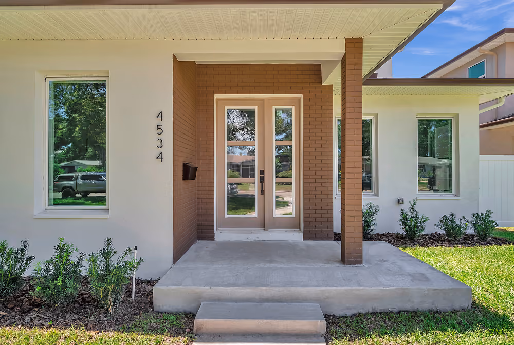 Modern house entrance with a glass double door, two windows, brick column, and house number 4534.