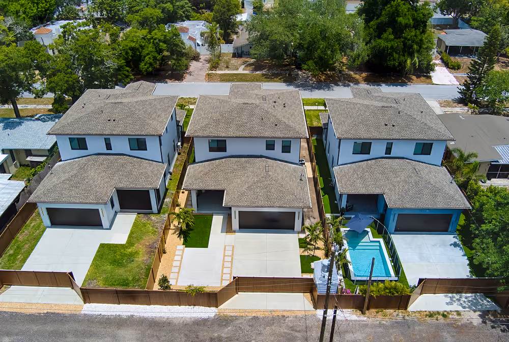 Aerial view of three modern two-story houses with driveways and a swimming pool in the rightmost house.