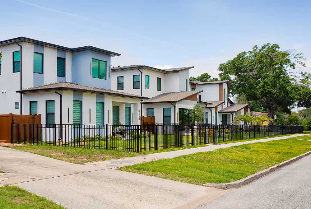 Modern two-story houses with green-tinted windows and fenced yards on a suburban street.
