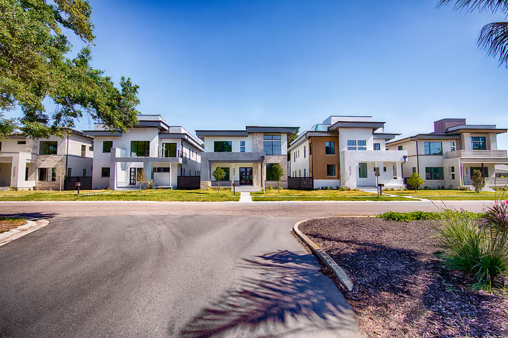 Modern two-story houses with clean lines and large windows under a clear blue sky.