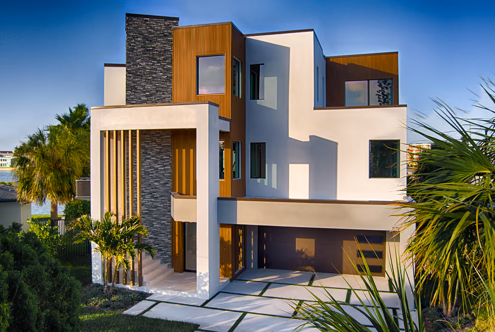 Modern three-story house with white, wood, and stone exterior and a two-car garage.