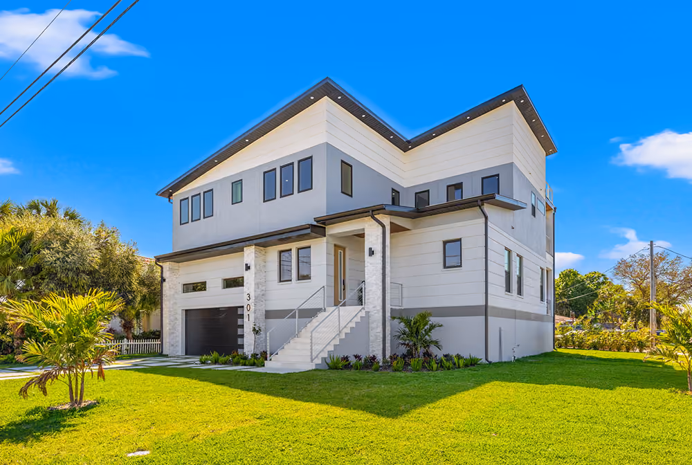 Modern two-story house with white and gray exterior and a front staircase on a sunny day.