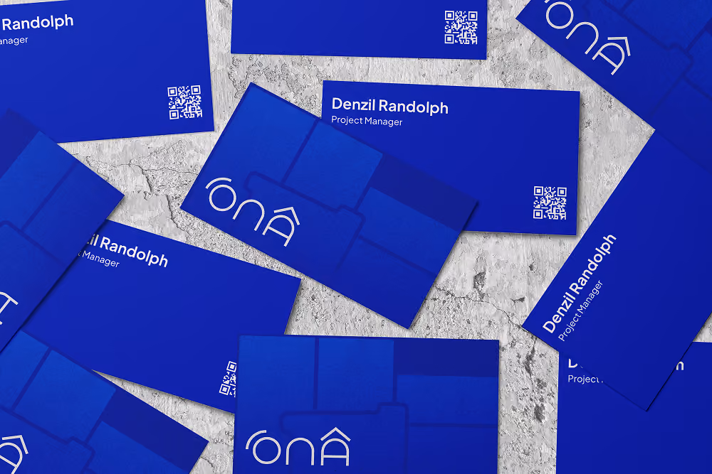 Blue business cards with the name Denzil Randolph, Project Manager, and a QR code, scattered on a textured surface.
