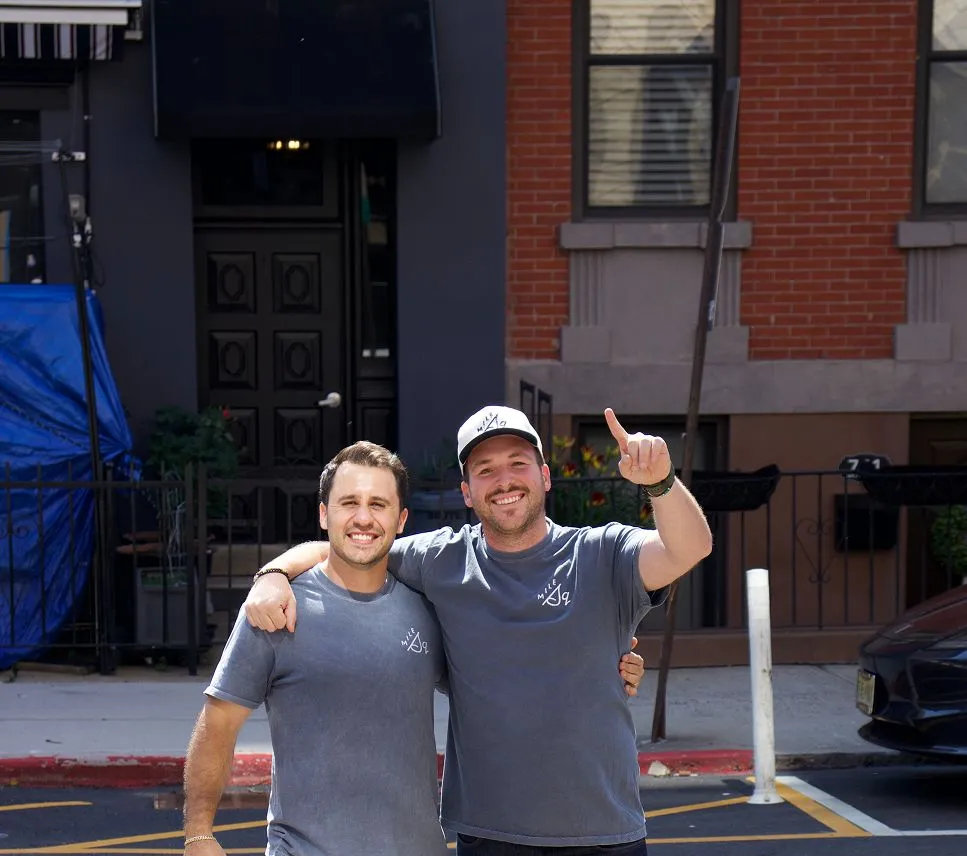 A couple of men standing next to each other in a parking lot.