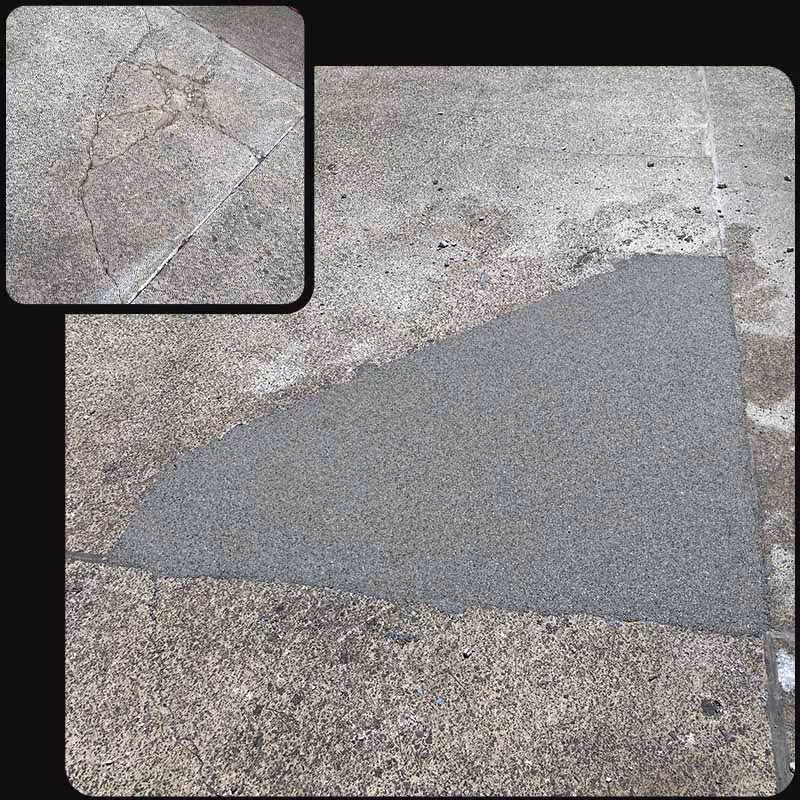 Concrete pavement with a newly repaired triangular patch shown against surrounding cracked surface.
