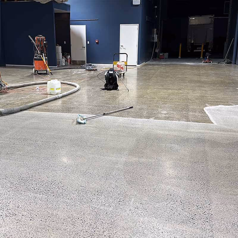 Indoor area with freshly polished concrete floor and industrial cleaning equipment visible.