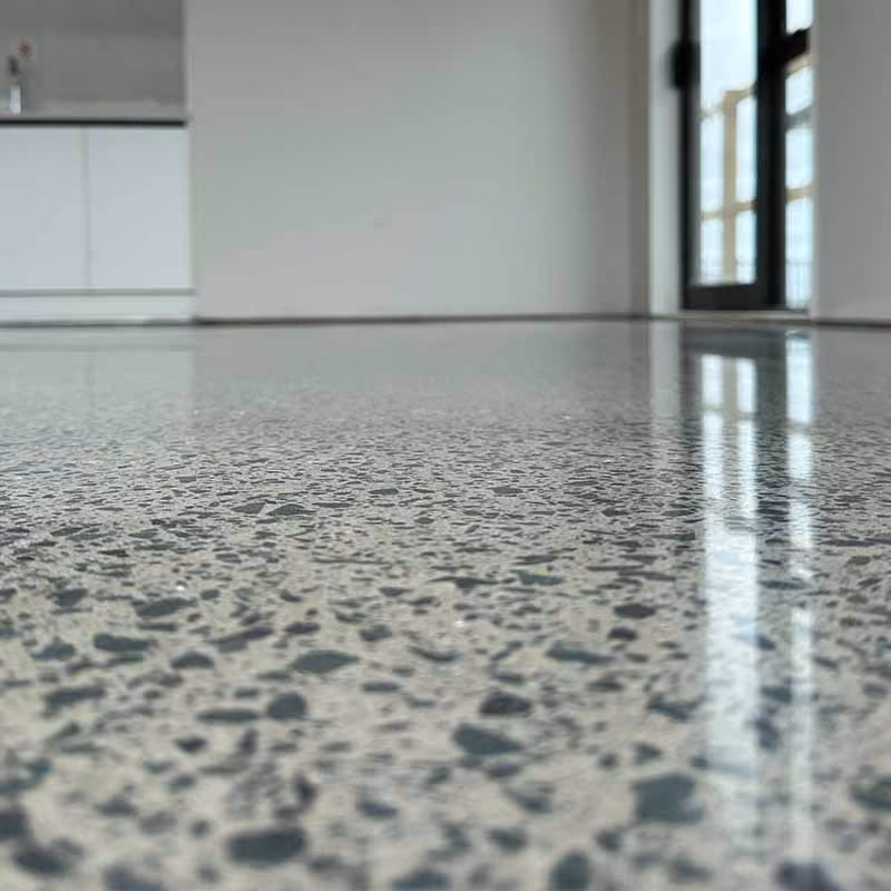 Polished terrazzo floor with reflected window light in a minimal modern room interior.