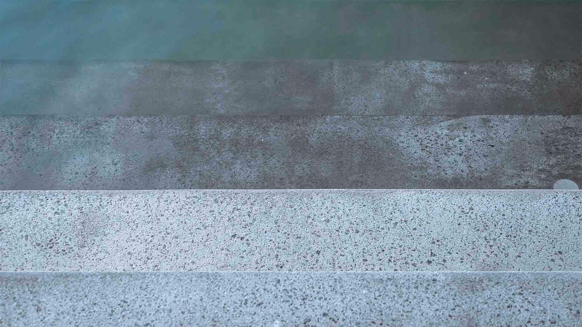 Close-up of four concrete steps with varying textures and shades of gray.