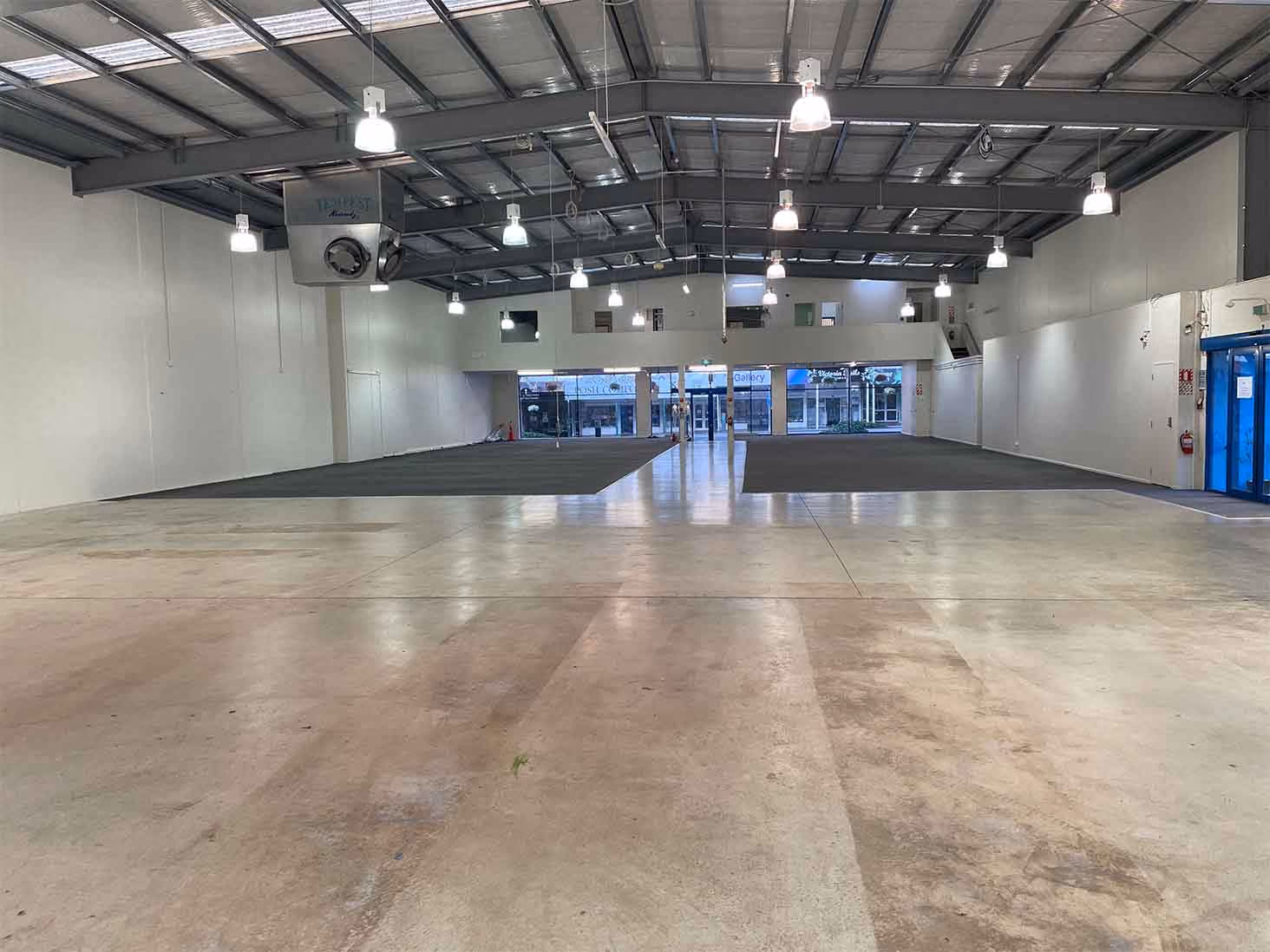 Empty commercial warehouse interior with polished concrete floor and high ceiling lights.