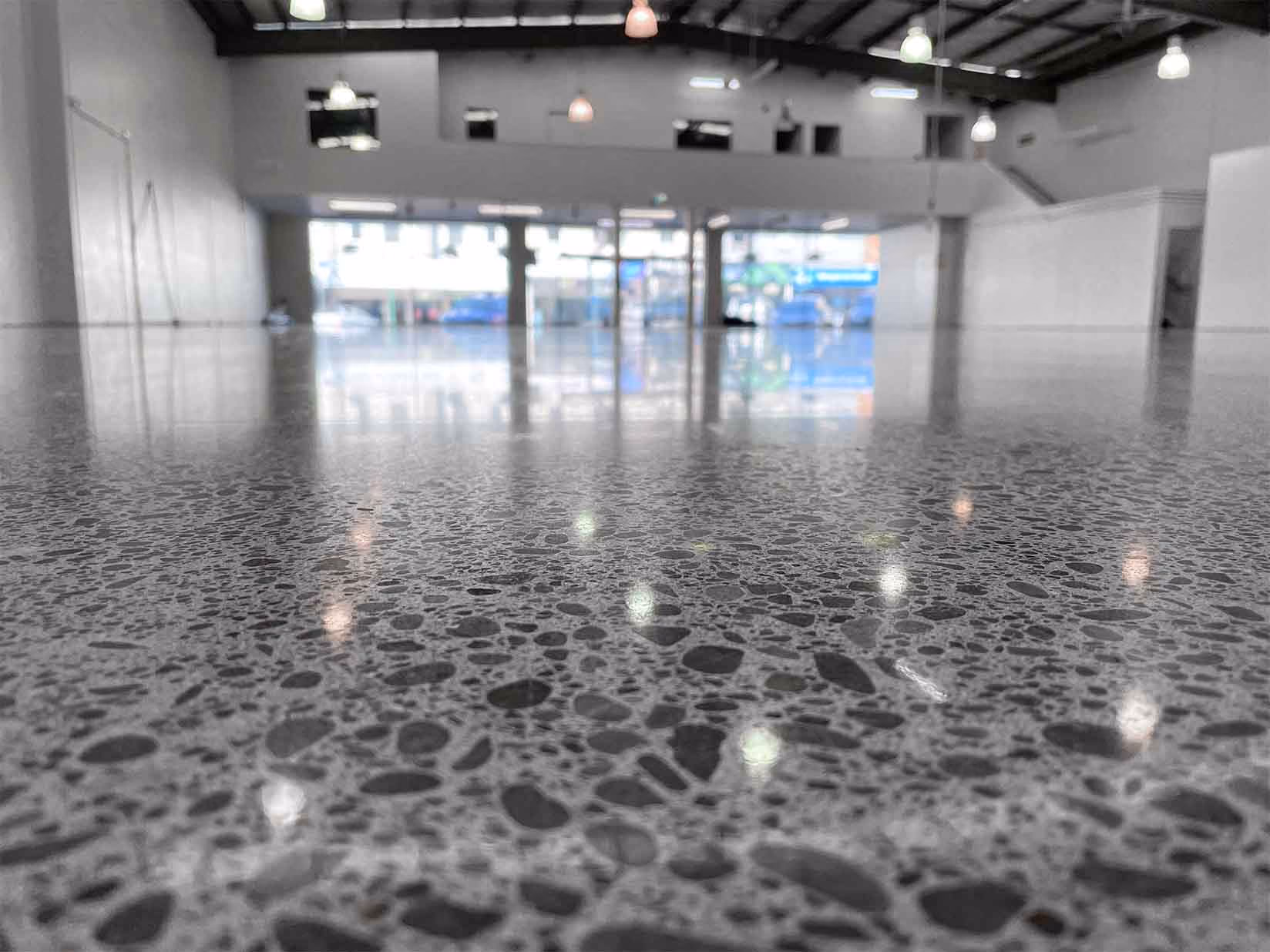Polished concrete floor reflecting ceiling lights in a large empty commercial space.