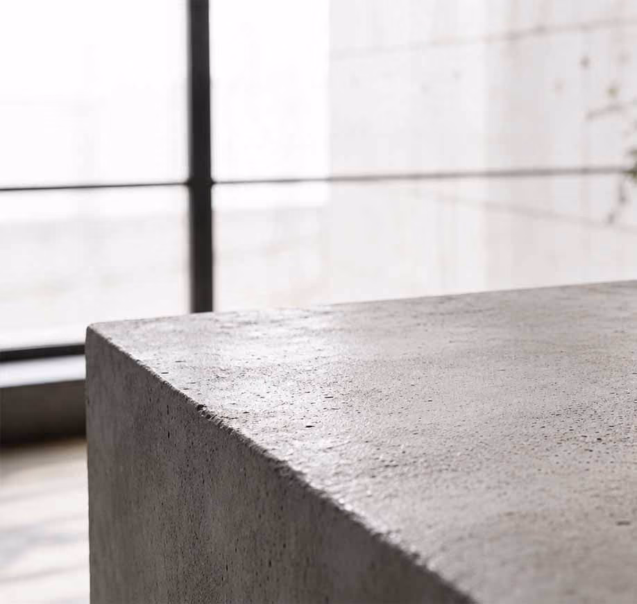 Close-up of a smooth, square concrete surface with natural light from window behind.