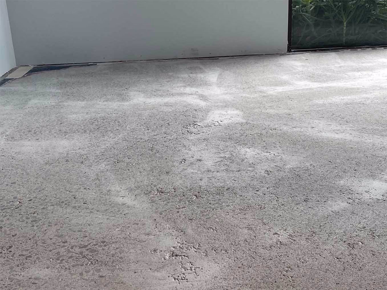 Smooth concrete surface with slight texture under a white wall and glass window corner.