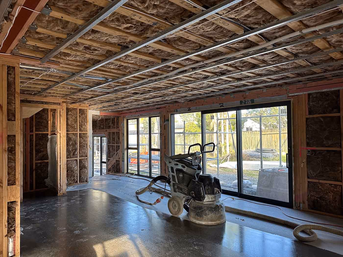 Interior of a partially constructed building with exposed insulation, framing, and construction equipment.