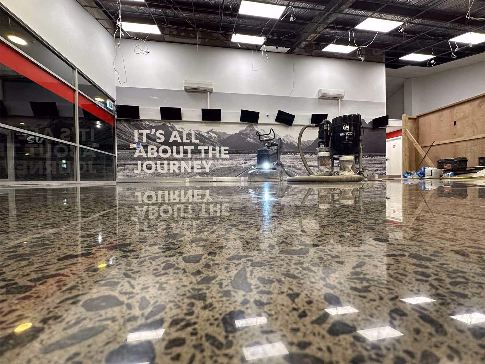 Polished stone floor reflecting ceiling lights and a wall sign reading 'IT'S ALL ABOUT THE JOURNEY'.