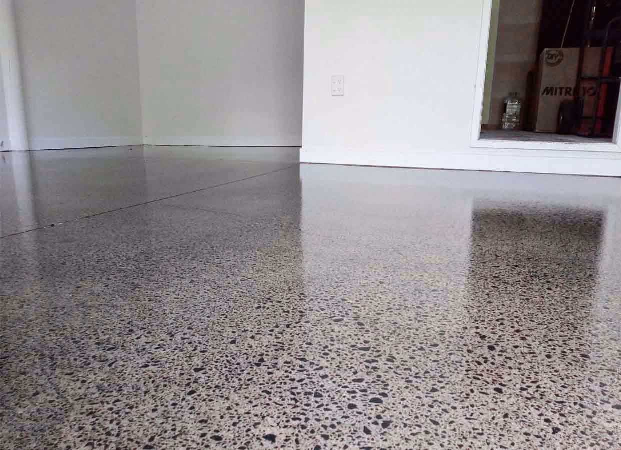 Shiny polished concrete floor inside a room with white walls and a small open storage space.