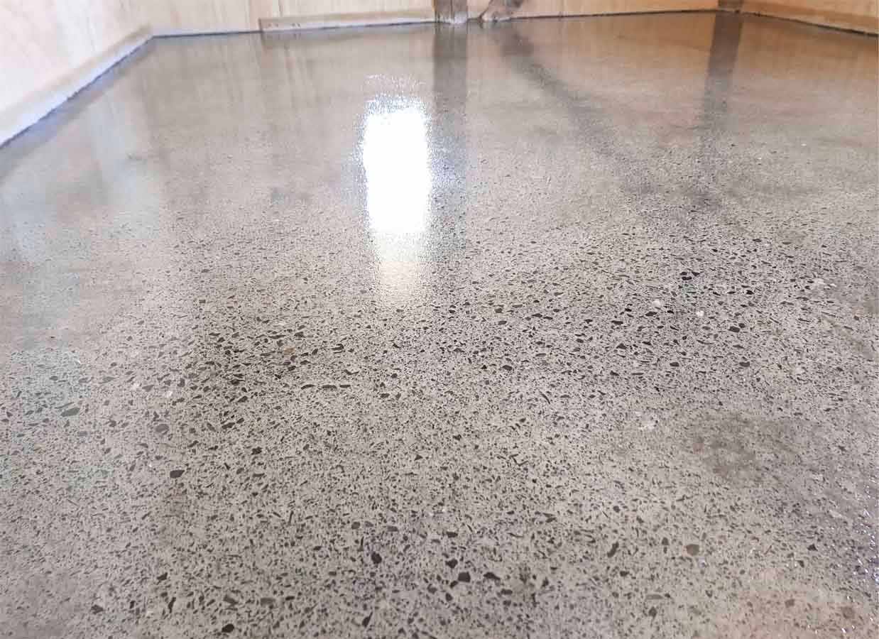 Shiny, newly polished concrete floor reflecting light in an empty room.