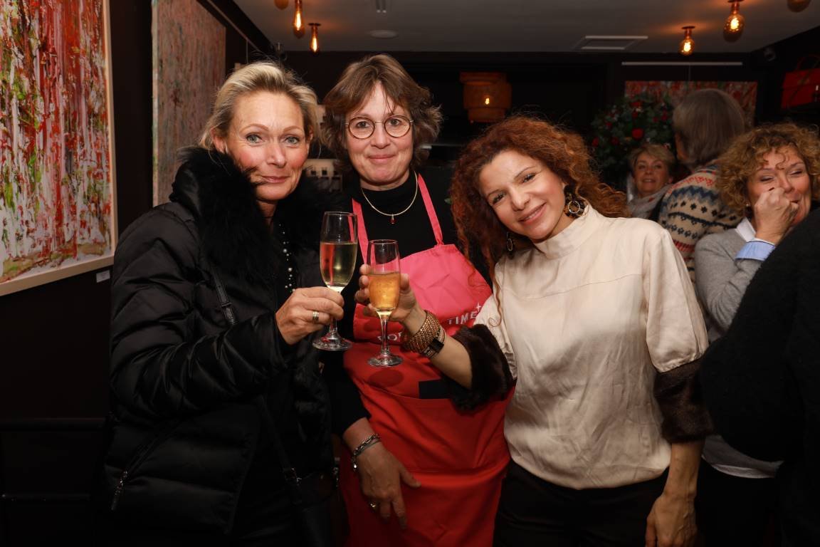 Trois dames posent en photo, un verre à la main.