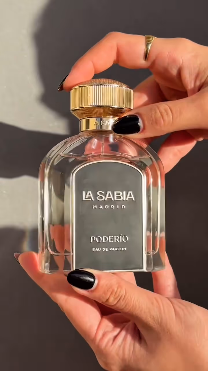 Hands with black nail polish holding La Sabia Madrid Poderío eau de parfum bottle.