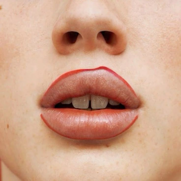 Close-up of lips with red lip liner slightly outside natural lip edge on pale skin.