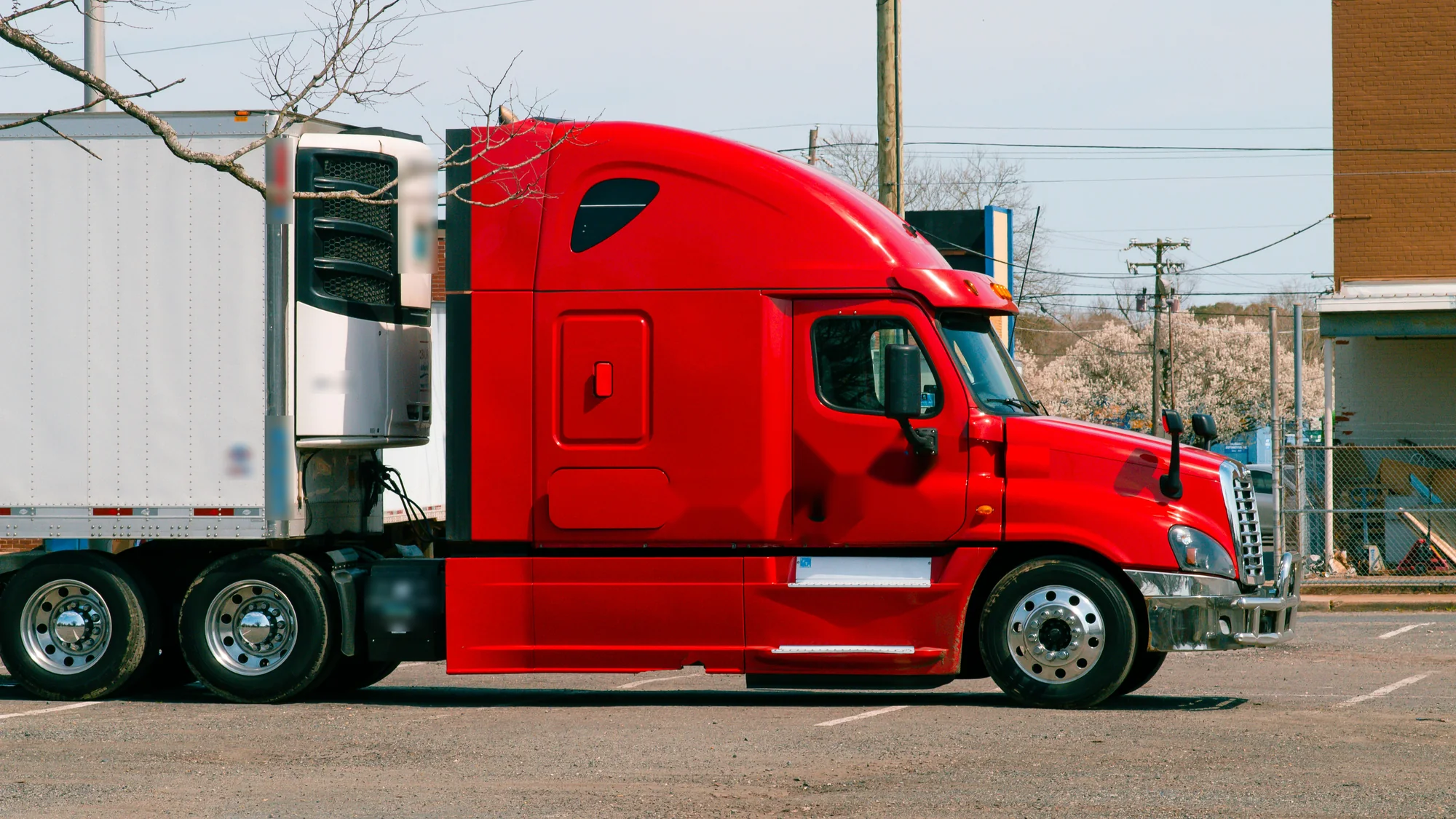 Refrigerated trailer with its cooling unit, hitched to a tractor parked in an empty lot