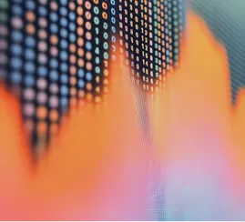Close-up of a digital stock market graph with orange and pink trend lines on LED screen dots.