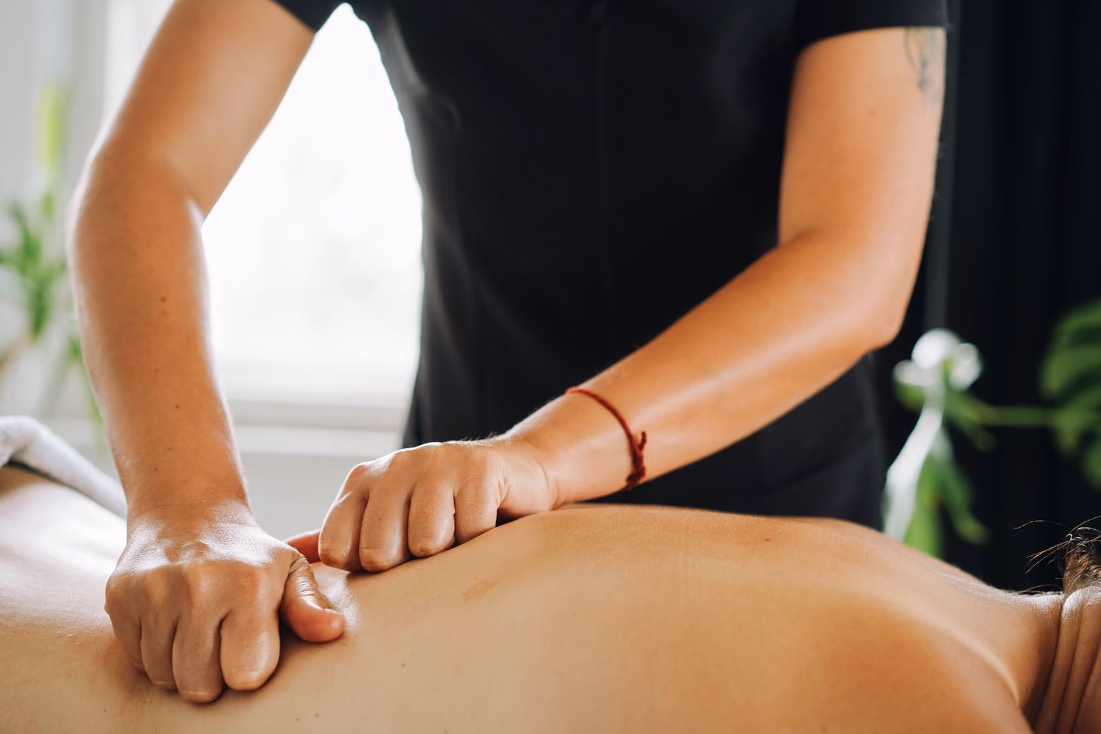 Massage therapist applying elbow pressure on a person's back during a massage session.