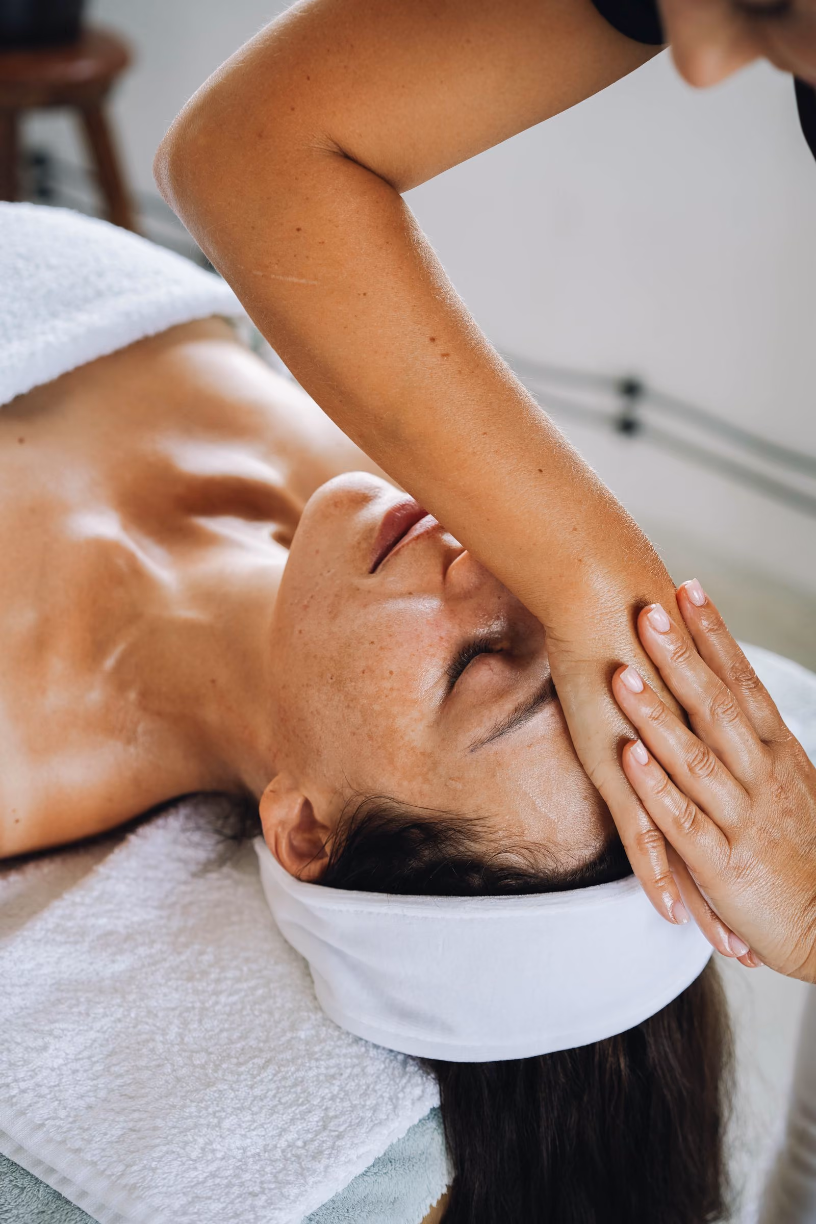 Woman receiving a relaxing facial massage with hands gently pressing her forehead.