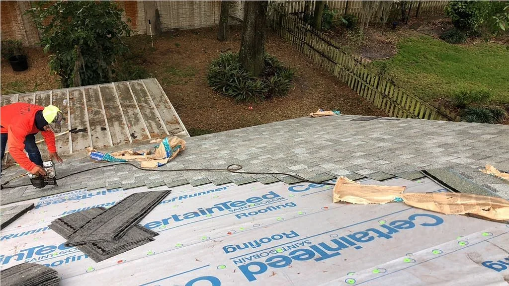 JTO roofing crew during a roof replacement tear-off with new shingle bundles staged on the deck