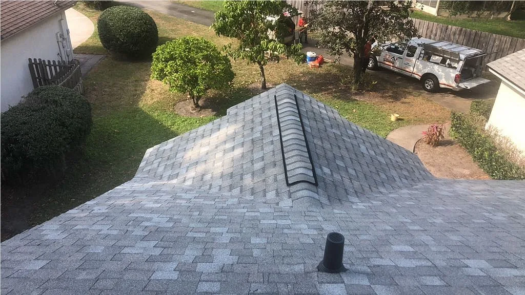 Aerial view of a freshly shingled gray roof with a JTO truck on the street during a roof inspection