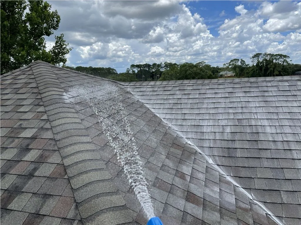Asphalt shingle roof being pressure washed during a JTO roof cleaning