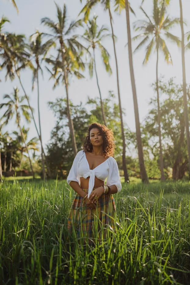 Portrait en lumière naturelle d'une femme en tenue bohème au milieu d'une végétation tropicale et de palmiers.