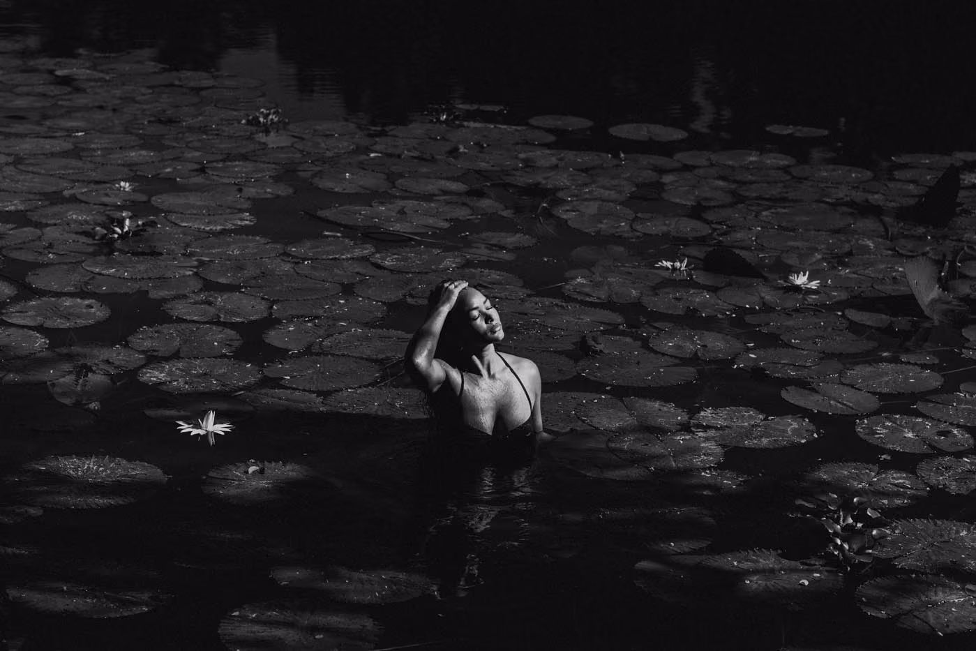 Plan large en noir et blanc en extérieur d'une femme posant dans un bassin de nénuphars à l'Étang Saint-Paul.