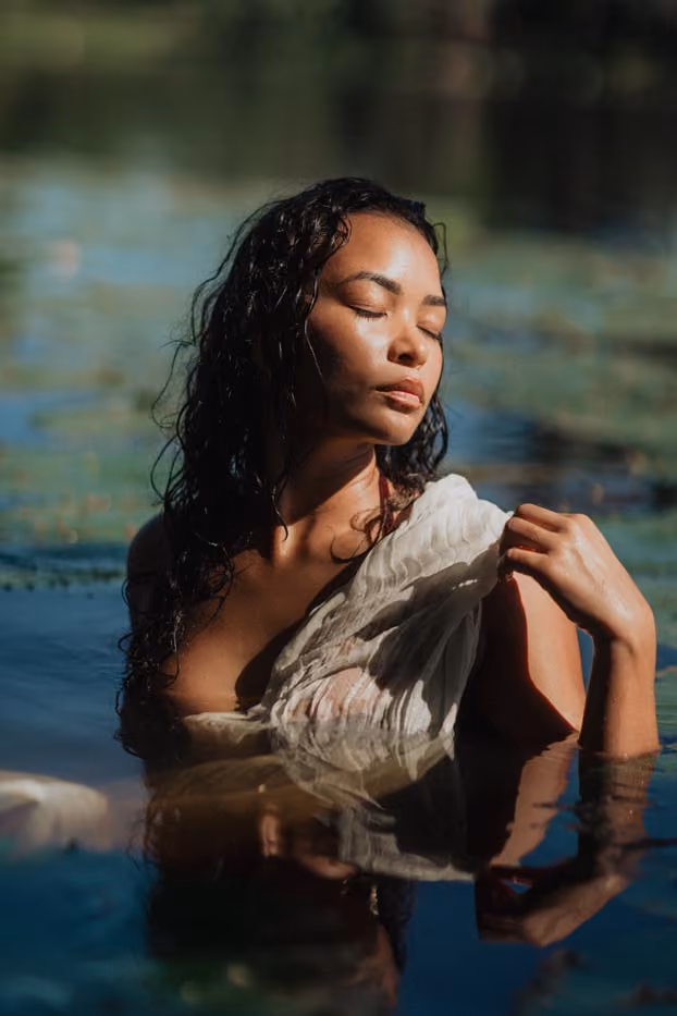 Séance photo portrait en extérieur d'une femme posant dans un bassin de nénuphars à la lumière du soleil couchant à l'Étang Saint-Paul.