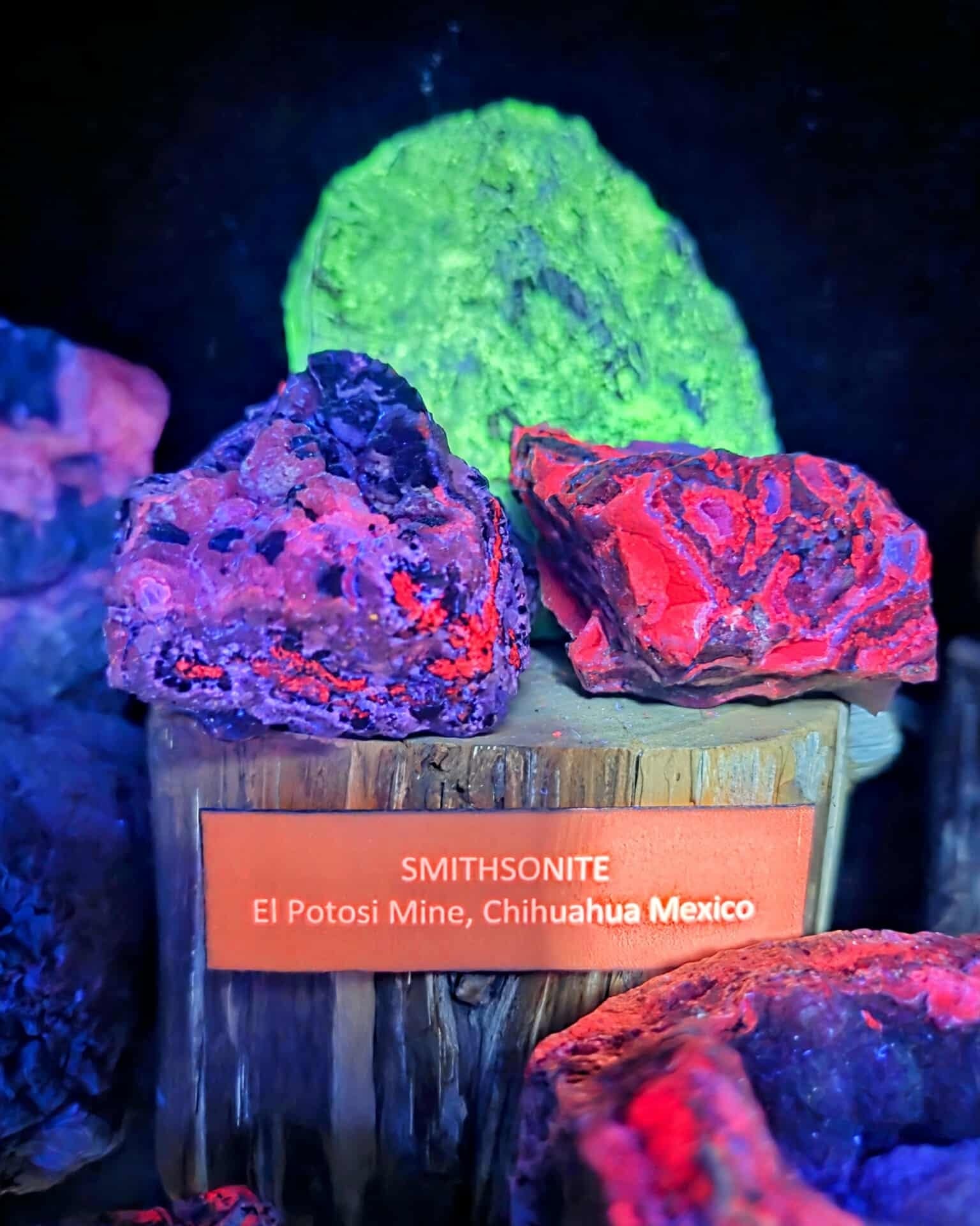 Fluorescent Smithsonite mineral samples glowing red, purple, and green from El Potosi Mine, Chihuahua, Mexico.