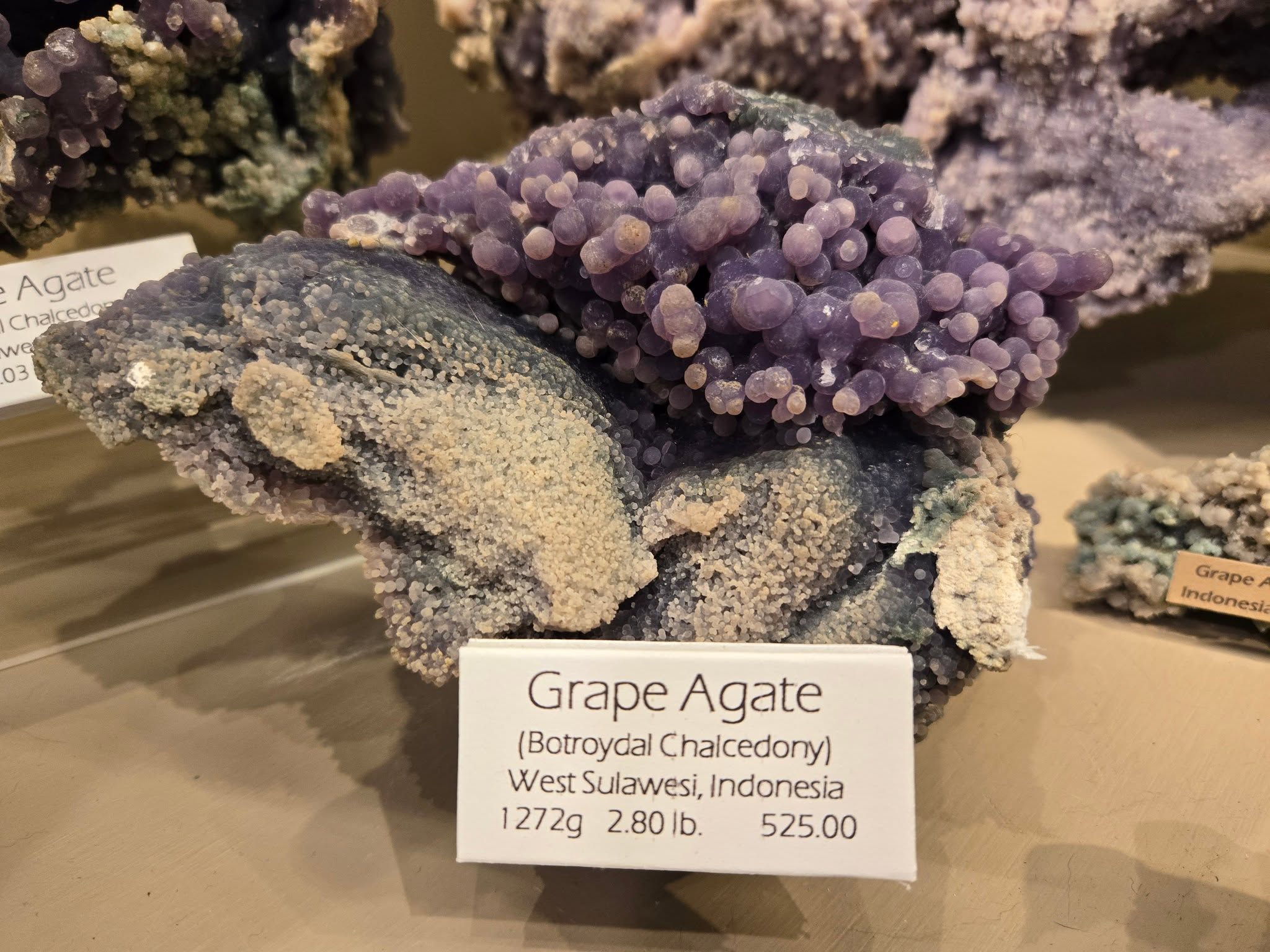Purple and beige grape agate mineral specimen with label from West Sulawesi, Indonesia.