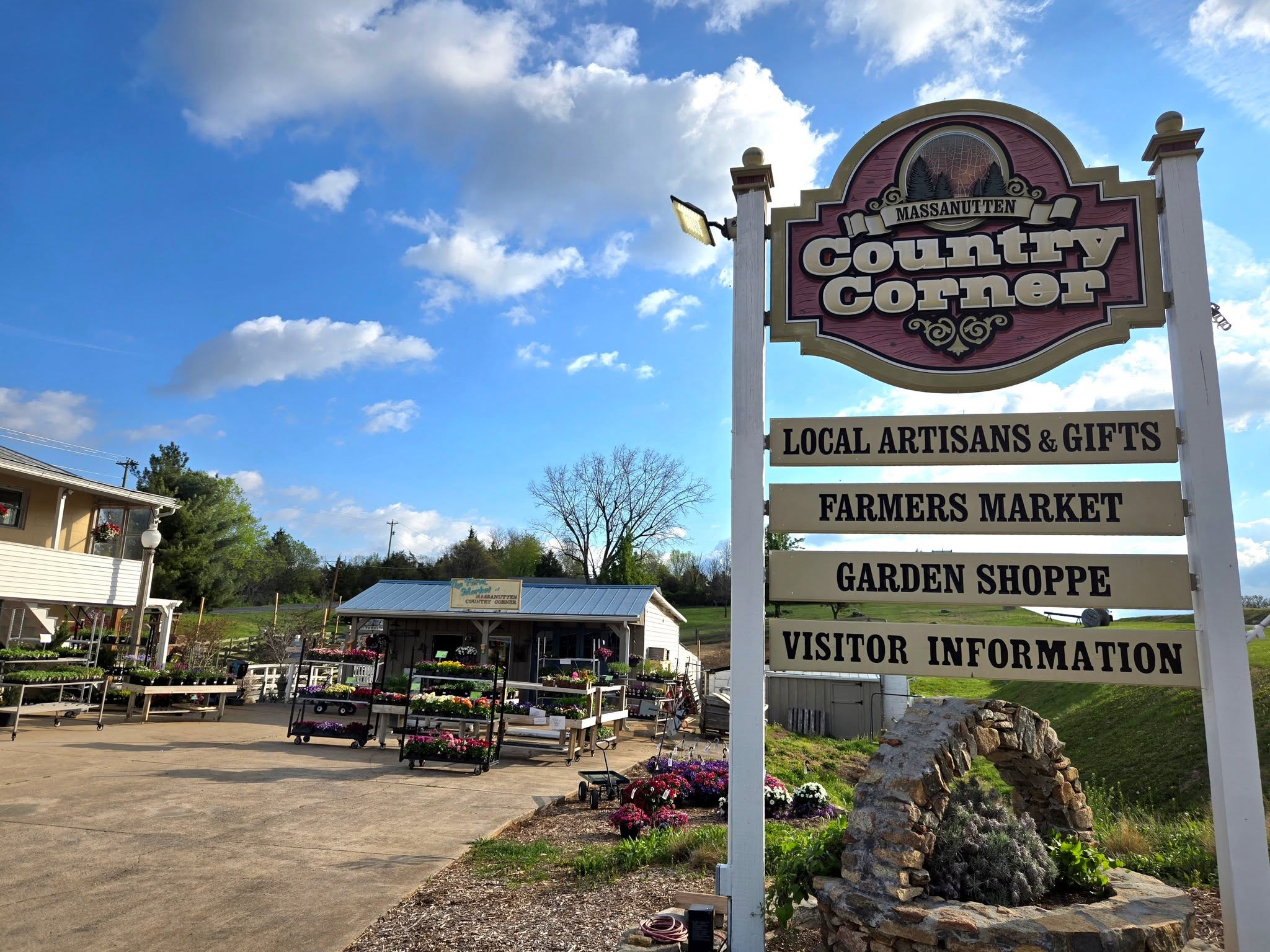 Outdoor market area with sign for Massanutten Country Corner listing local artisans, farmers market, garden shoppe, and info.